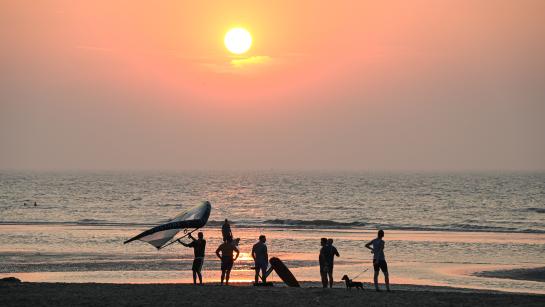 wingsurfers op het strand bij zonsondergang